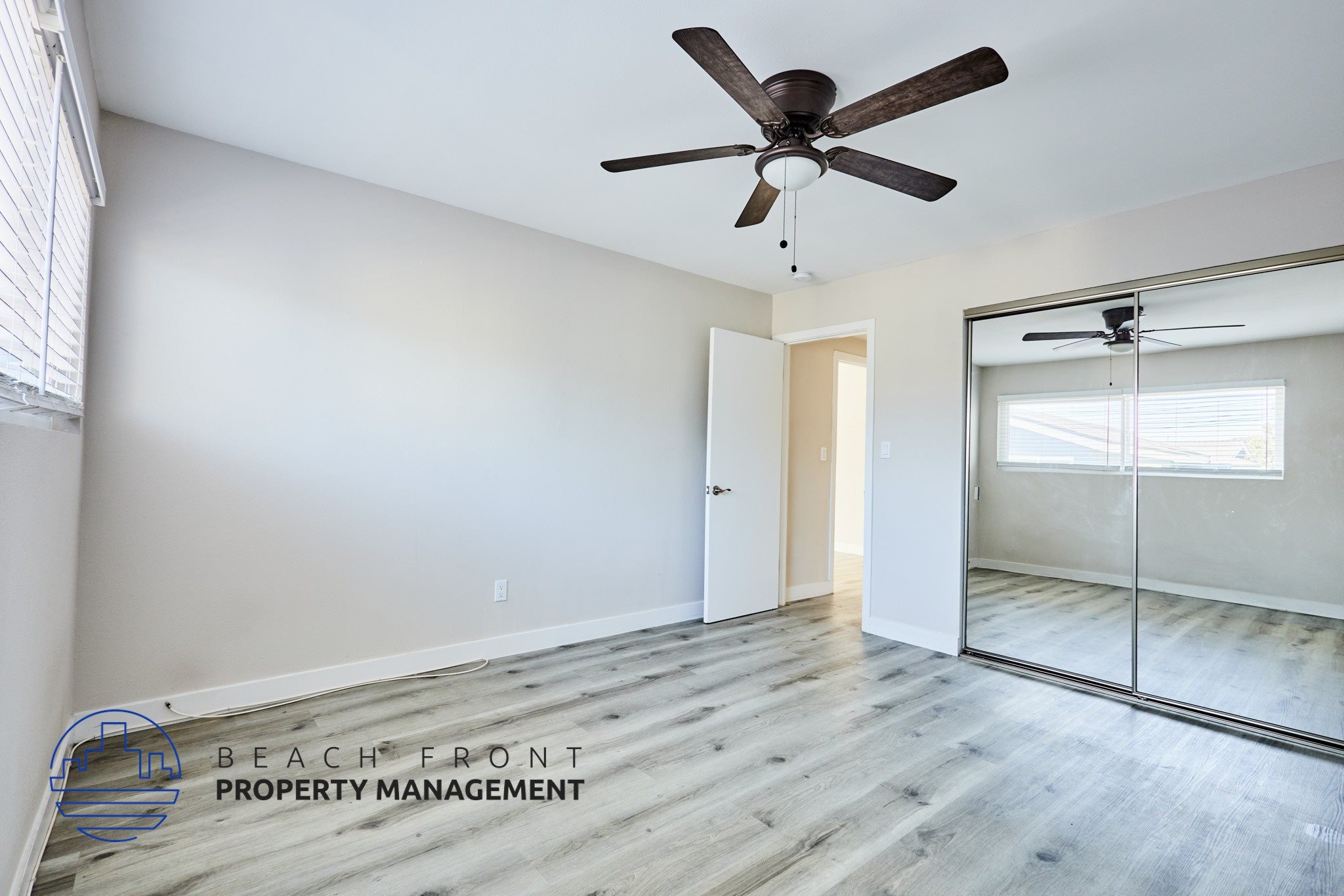 A spacious room with a ceiling fan and sliding glass doors leading to a balcony.